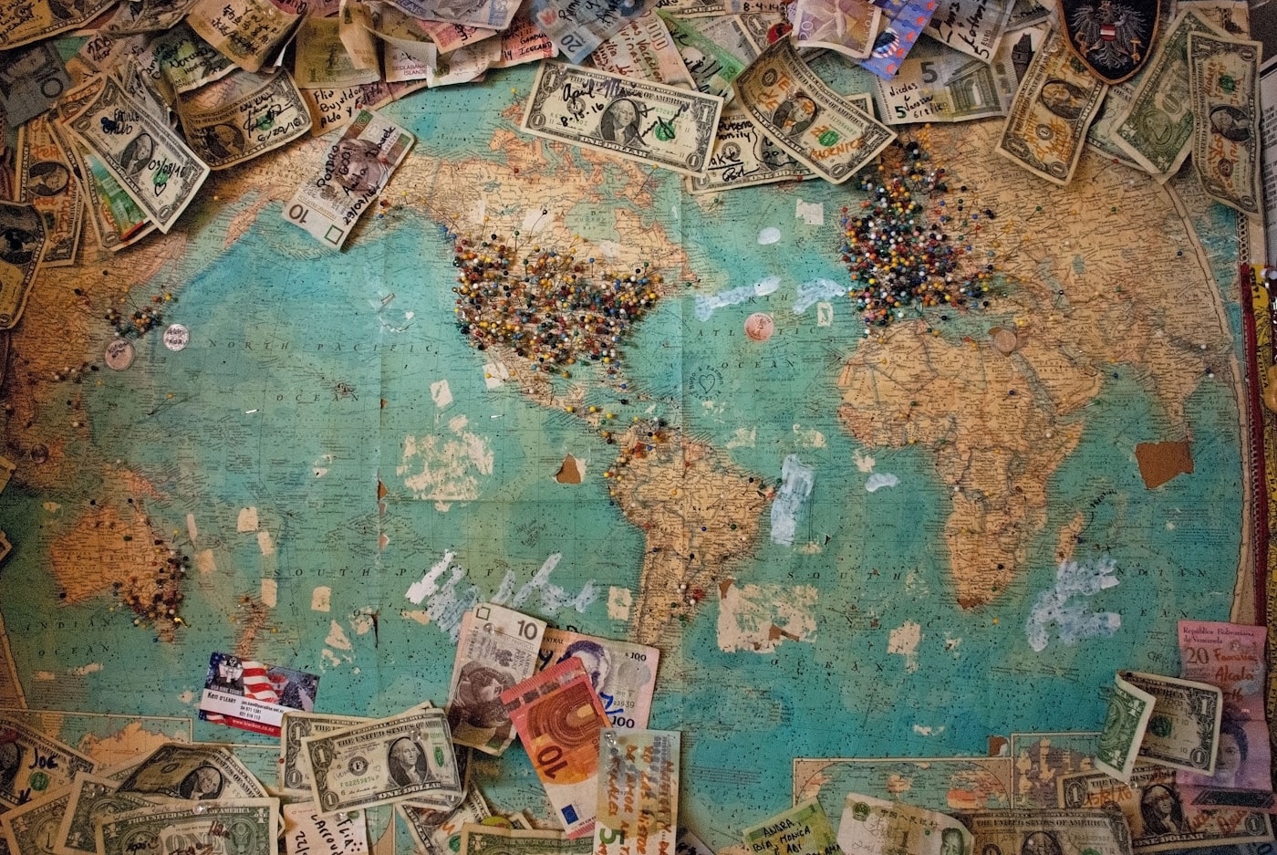 A vintage world map with international currency surrounding it, representing journeys across borders
